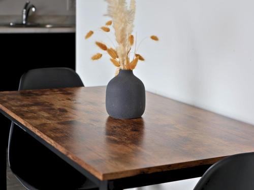 a black vase sitting on top of a wooden table at Logîtel Rimouski in Rimouski