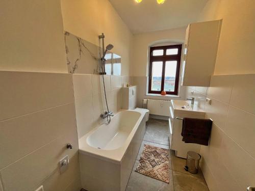 Baño blanco con bañera y lavamanos en kleine feine Wohnung mit Balkon, en Görlitz