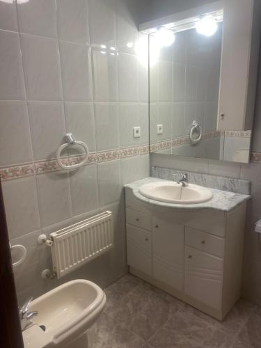 La salle de bains blanche est pourvue d'un lavabo et d'un miroir. dans l'établissement Apartamento Isabela3, à Cangas de Onís
