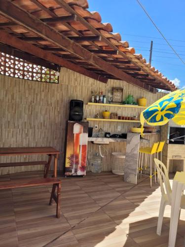 a patio with a bench and an umbrella at Casa Meu Cantinho in Barra de São Miguel