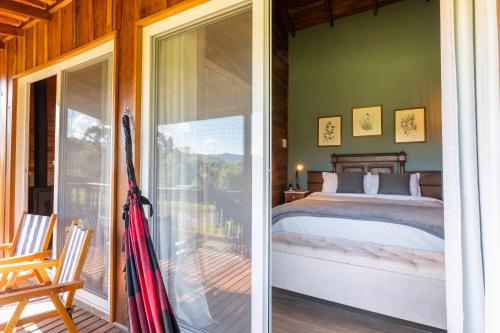 een slaapkamer met een bed en een glazen schuifdeur bij Cabanas da Fazenda in Gramado
