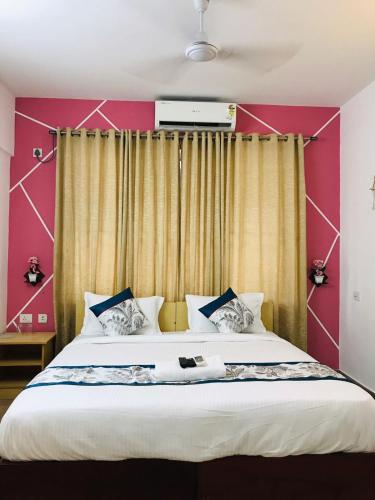 a bedroom with a large bed with a red wall at Melvet Residency in Cochin