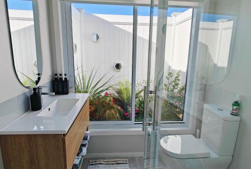 a bathroom with a toilet and a sink and a window at Secret Garden Guest Suite in Tauranga