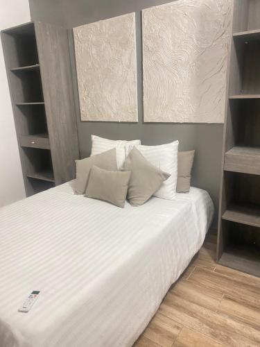 1 cama con sábanas blancas y almohadas en una habitación en L'hibicus en Sainte-Marie
