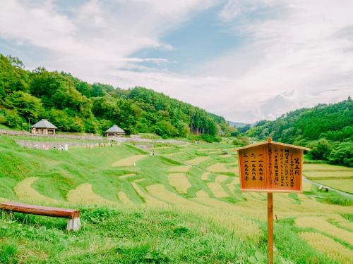 a field of rice terraces with a sign in the foreground at Fudouonsen Sawaya in Shimojo mura