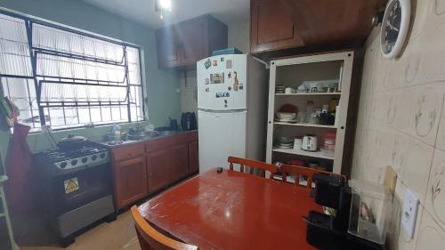 een keuken met een fornuis, een koelkast en een tafel bij La casa in Santana do Livramento