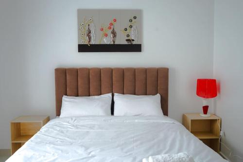a bedroom with a large bed with white sheets and a red lamp at Appartement Chic et Luxueux Corniche Tanger in Tangier