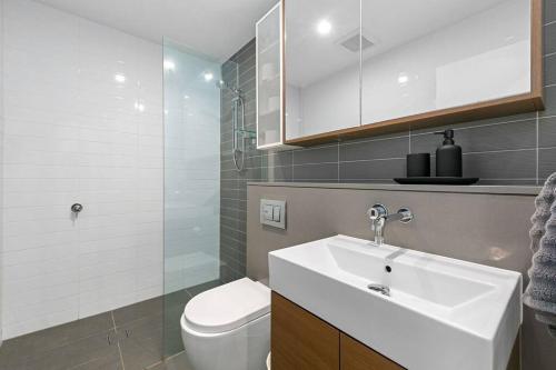 a bathroom with a white sink and a toilet at Luxury Waterfront 2 Bed near Olympic Park & Parra in Sydney