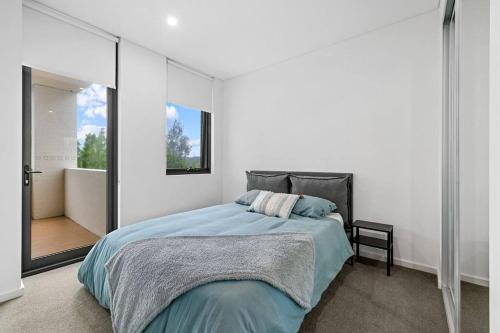 a bedroom with a large bed and a balcony at Luxury Waterfront 2 Bed near Olympic Park & Parra in Sydney