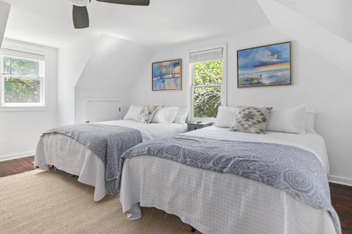 two beds in a white room with two windows at Sawyer's Landing- Mins to beach & Dtwn in Charleston