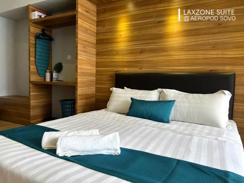a bedroom with a large bed with a wooden wall at Aeropod Sovo Tanjung Aru Kota Kinabalu in Kota Kinabalu