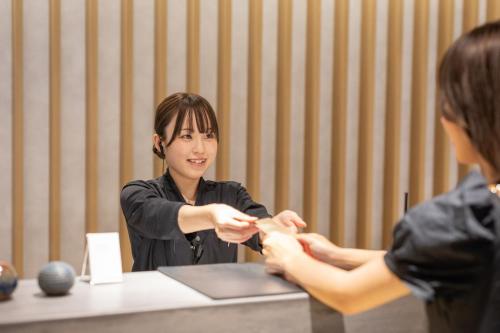 a woman sitting at a table cutting a persons finger at OND HOTEL（オンドホテル） in Takeo