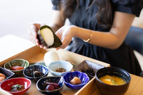 a woman holding a tray of food with sushi at OND HOTEL（オンドホテル） in Takeo