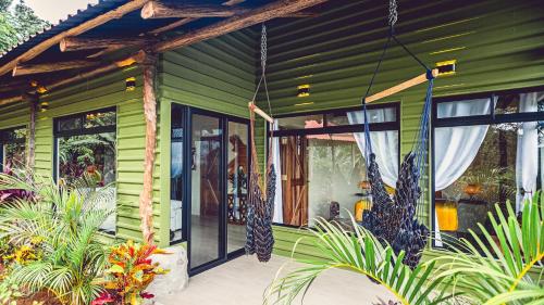 a green house with a porch with plants at Cabañas Caeli, El Toucan, Peaceful Rainforest Retreat with Stunning Views in Fortuna