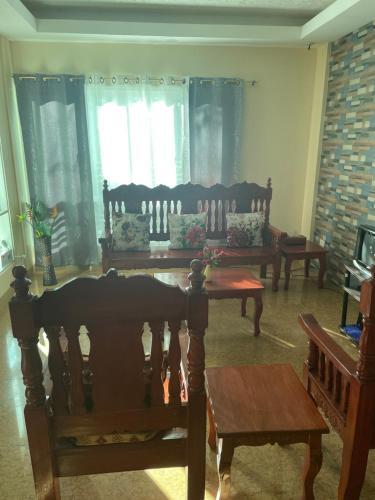 ein Wohnzimmer mit Stühlen, einem Tisch und Fenstern in der Unterkunft Adventurer's Vacation Home in Alaminos