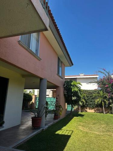 a house with a grass yard next to a building at Casa de los abuelos in Jiutepec