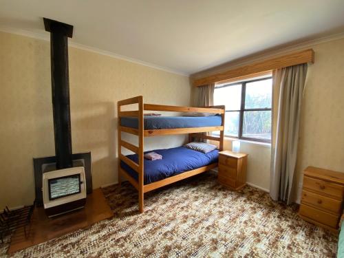 a bedroom with two bunk beds and a fireplace at The Vintage Flat - Retro Charm in Tyrolean Village in Jindabyne