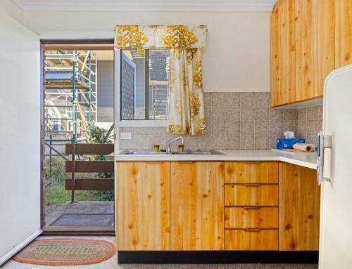 a kitchen with a sink and an open door at The Vintage Flat - Retro Charm in Tyrolean Village in Jindabyne
