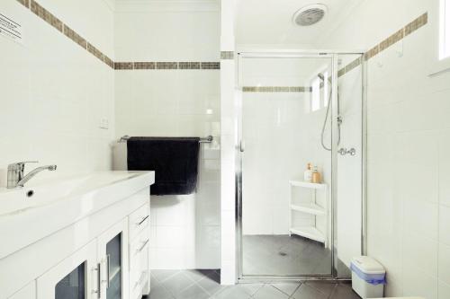 a white bathroom with a shower and a sink at 2 BR Granny Flat Near Airport in West Richmond