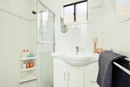 a white bathroom with a sink and a shower at 1 BR Granny Flat near Airport in West Richmond