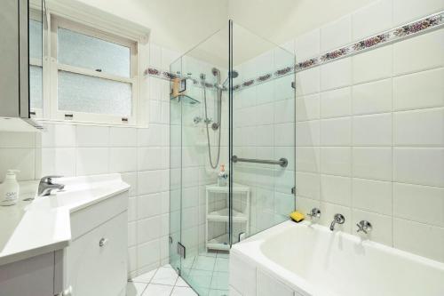 a white bathroom with a shower and a sink at 3 BR House Near Airport in West Richmond