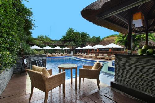 a patio area with chairs, tables, chairs and umbrellas at AlamKulkul Boutique Resort in Kuta