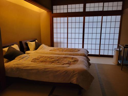 a bedroom with two beds in front of a window at Tsukimotoya Ryokan in Toyooka