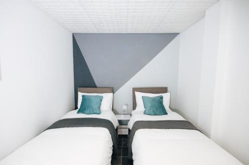 two beds in a room with white walls and blue pillows at Modern Home - Contractors welcome in Cheshunt