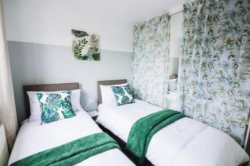two beds in a small room with green and white at Convenient Stay for ALL OCCASIONS in Cheshunt