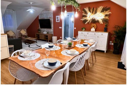 une grande table en bois avec des chaises blanches et une salle à manger dans l'établissement L'évasion appart, proche disney, 8 pers., à Collégien