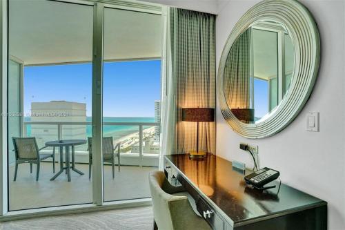 einen Schreibtisch in einem Zimmer mit einem Spiegel und einem Tisch in der Unterkunft Fontainebleau Miami Beach in Miami Beach