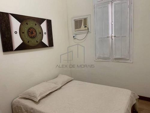 1 dormitorio con 1 cama y reloj en la pared en Pousada Vôo dos Beija-Flores, en Vitória