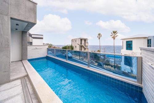 a swimming pool on the balcony of a house with the ocean at Ddosi Aewol Pool Villa in Jeju