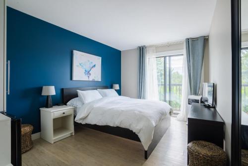 Dormitorio azul con cama y ventana en Crawford View en Kelowna