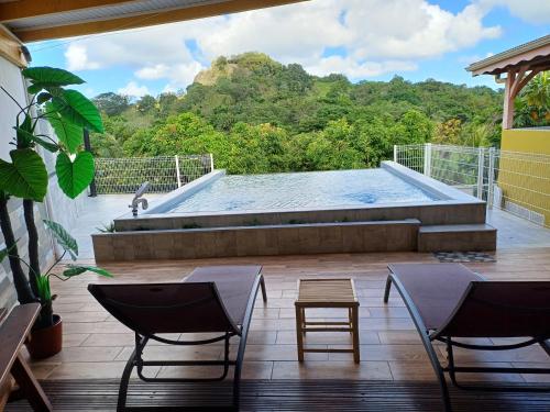 a swimming pool on a deck with chairs and a table at Le Nid De Nicolas in Saint Esprit