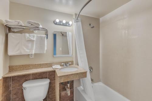 La salle de bains est pourvue de toilettes, d'un lavabo et d'une douche. dans l'établissement Viking Motel-Detroit, à Detroit