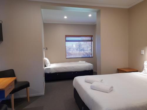 Tongariro Junction Accommodation في تورانجي: غرفة فندقية بسريرين ونافذة