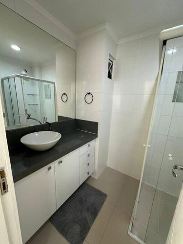 a bathroom with a sink and a glass shower at Excelente Apto em Bal. Camboriú in Balneário Camboriú
