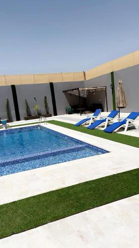 a swimming pool with blue lounge chairs next to a building at شاليه نايا in Kerak
