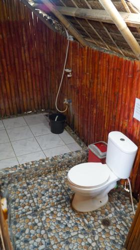 ein Bad mit einem WC in einer Holzwand in der Unterkunft Magindara Guesthouse in Caramoan