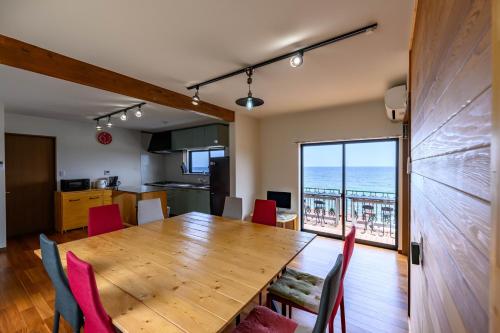 a dining room with a wooden table and red chairs at taiza house in Kyotango