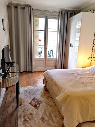une chambre avec un lit, une télévision et une fenêtre dans l'établissement Grand Appartement Paris 16ème, à Paris