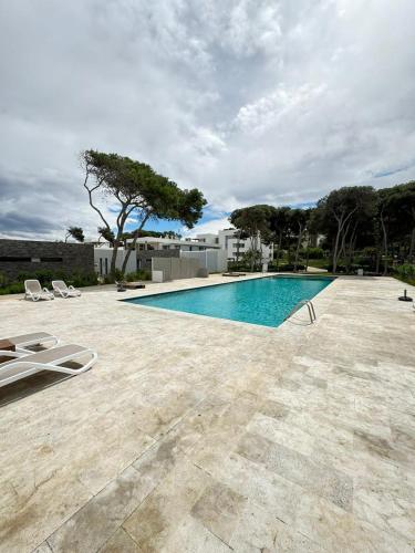 uma piscina num quintal com duas cadeiras de jardim em Appartments VIP Al Hoceima Sfiha em Al Hoceïma