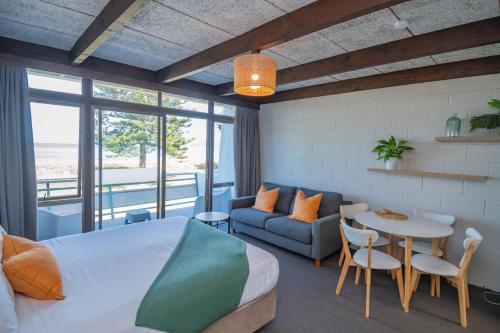 1 dormitorio con cama, mesa y sofá en Whispering Sands Beachfront Motel, en Gisborne