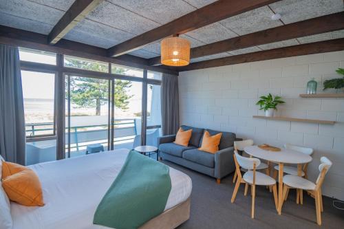ギズボーンにあるWhispering Sands Beachfront Motelのベッドルーム1室(ベッド1台、テーブル、ソファ付)