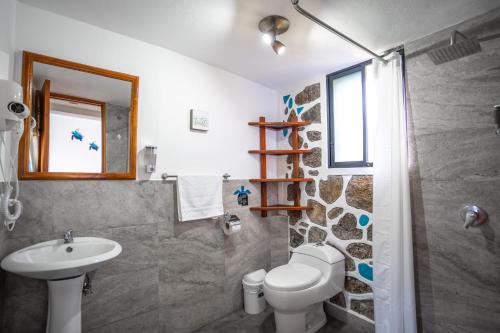 bagno con servizi igienici bianchi e lavandino di Maidith Galapagos Inn a Puerto Ayora