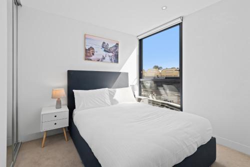 1 dormitorio con cama blanca y ventana en Bright CBD Apartment 2-Minutes To Gardens & Market, en Melbourne