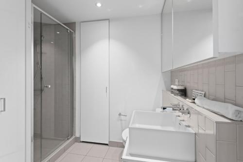 baño blanco con ducha y lavamanos en Bright CBD Apartment 2-Minutes To Gardens & Market, en Melbourne