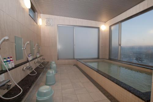 a bathroom with a swimming pool with a large window at Omura Station Hotel in Omura