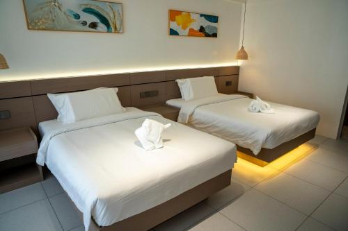 2 Betten in einem Hotelzimmer mit weißer Bettwäsche in der Unterkunft Willander Resort in Panglao
